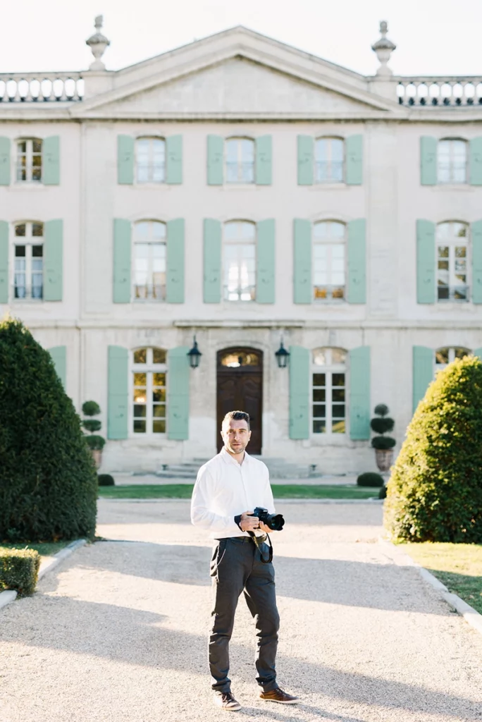 Photographe de mariage en Provence tenant son appareil photo devant un château.