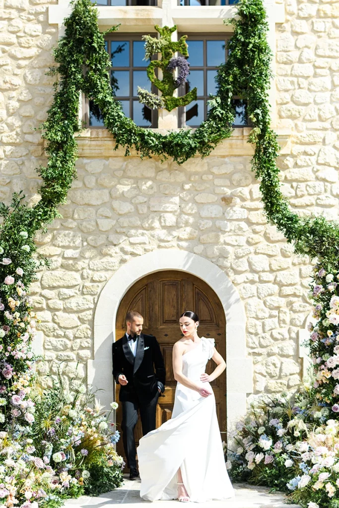 Couple de mariés devant une arche florale au Domaine du Mas de Rey à Arles en Provence